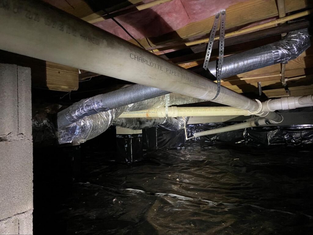 Crawl space with ductwork and vapor barrier in progress as part of a crawl space restoration project