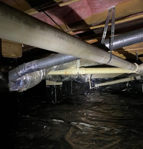 Crawl space with ductwork and vapor barrier in progress as part of a crawl space restoration project