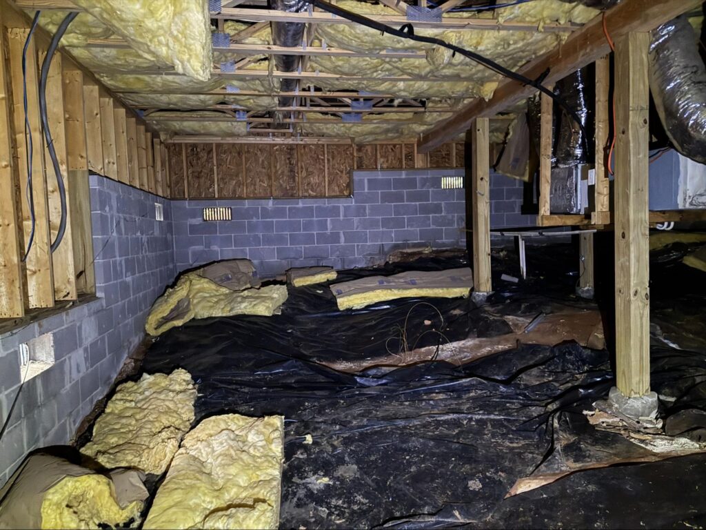 Crawl space with fallen insulation and moisture damage, showing the need for full crawl space restoration